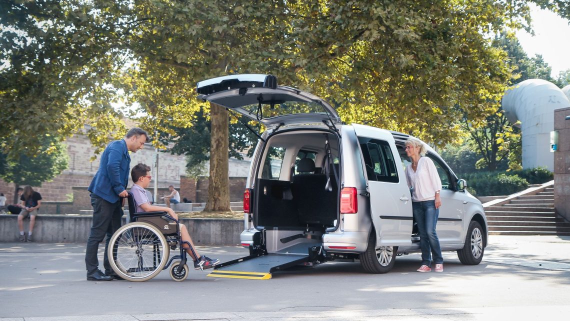 famille avec enfant en fauteuil roulant utilisant la rampe pour accéder à la voiture volkswagen tpmr